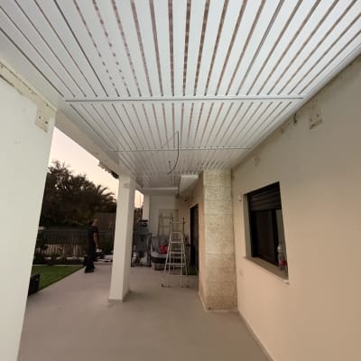 פרגולה מאלומיניום עם סולם ועובד ברקע