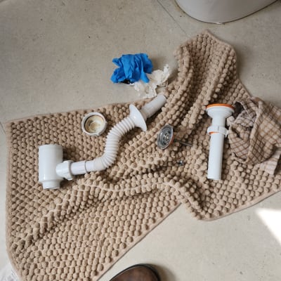 כלים וחלקי אינסטלציה על שטיח אמבטיה