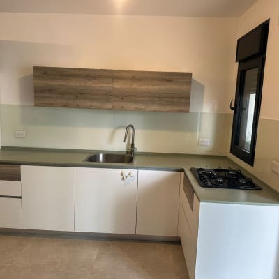 מטבח עם חיפוי זכוכית מעל השיש והכיור