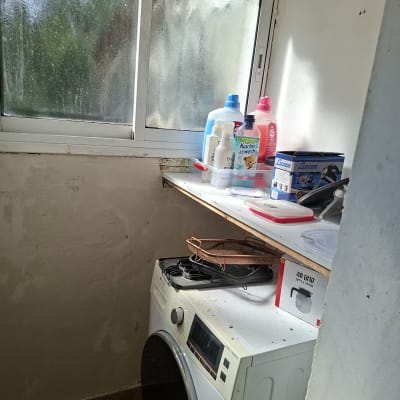 מכונת כביסה עם חומרי ניקוי על מדף ליד חלון