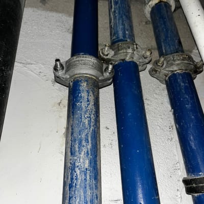 צינורות כחולים עם מחברים מתכתיים על קיר לבן