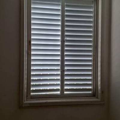 תריסים לבנים סגורים על חלון מלבני