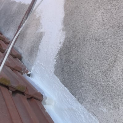 קיר מטויח בלבן מעל גג רעפים אדום