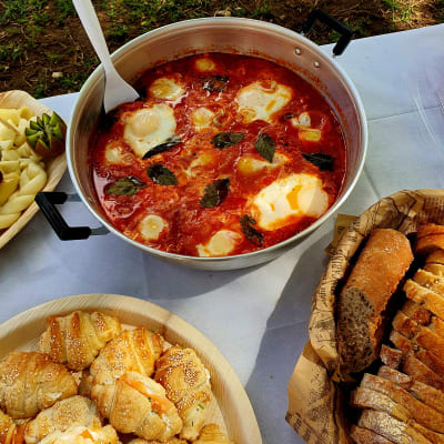 סיר שקשוקה עם ביצים ועשבי תיבול על שולחן קייטרינג