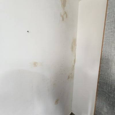 קיר עם כתמי רטיבות וכלי עבודה על הרצפה