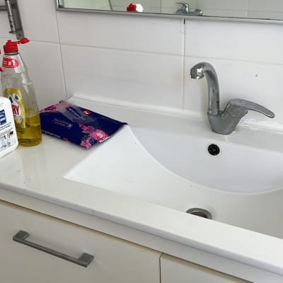 כיור עם ברז ומוצרי ניקוי על השיש