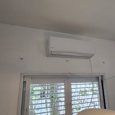 מזגן מותקן על קיר מעל חלון עם תריסים