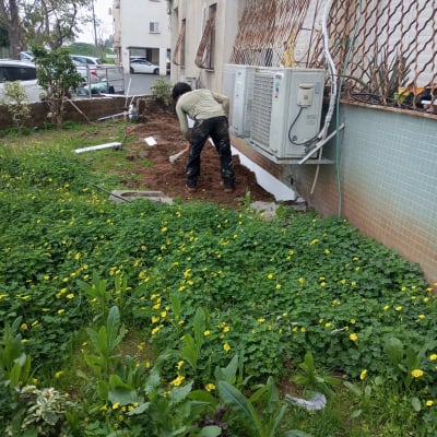 אדם חופר באדמה ליד קיר עם מזגנים