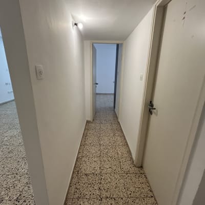 מסדרון צבוע בלבן עם דלתות ורצפת אריחים