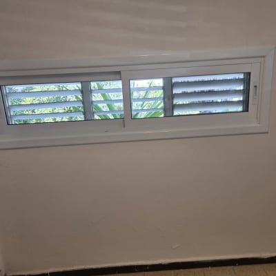 חלון הזזה לבן מאלומיניום עם תריסי שלבים המותקן בקיר