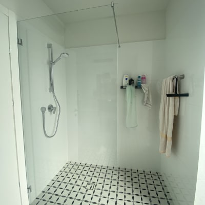 מקלחת עם ראש מקלחת, מגבות ומוצרי טיפוח על מדף