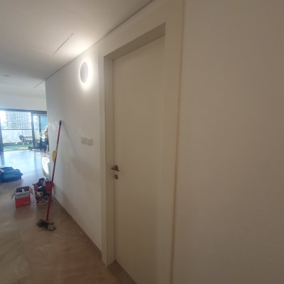 דלת לבנה עם ידית מתכת על קיר לבן