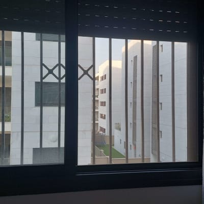 חלון עם סורגים מול בניינים לבנים