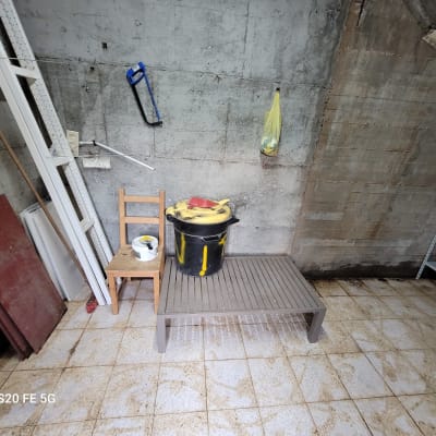 חדר עם כלים לניקוי, דלי ומגב על הקיר