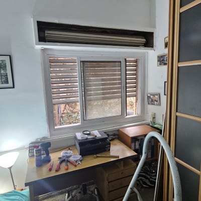 תריסים חומים פתוחים למחצה בחלון לבן