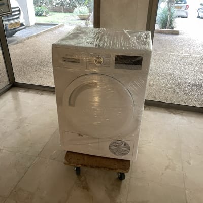 מכונת כביסה עטופה בניילון על עגלה עם גלגלים