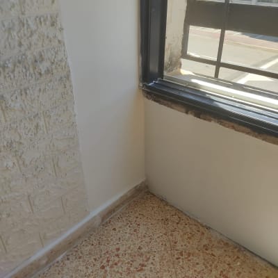 פינת קיר צבועה ליד חלון עם מסגרת שחורה