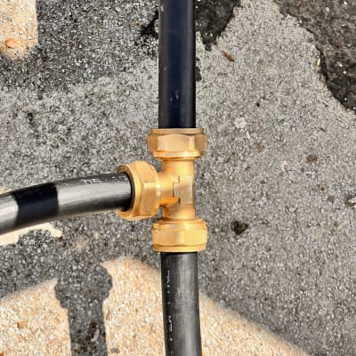 חיבור צינורות פלסטיק עם מחבר מתכת על אספלט