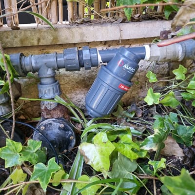 מסנן מים בגינה עם צינורות ועלים ירוקים