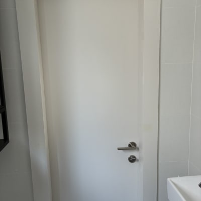דלת לבנה עם ידית מתכת בחדר אמבטיה