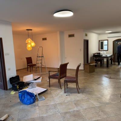 חדר עם סולם, כיסאות, ופח צבע על הרצפה