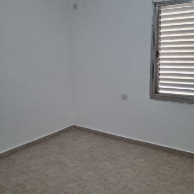 חדר ריק עם קירות לבנים ורצפת אריחים