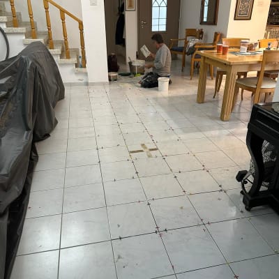 אדם מתקין אריחי רצפה עם דבק וכלים