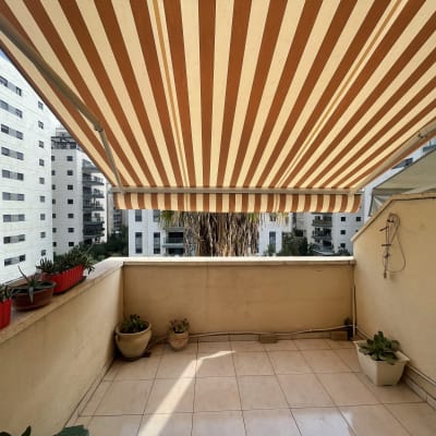 מרפסת עם סוכך מפוספס בצבעים חום ולבן