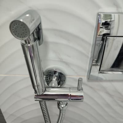 ברז כרום עם צינור גמיש על קיר לבן