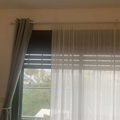 וילון תלוי על מוט מעל חלון זכוכית