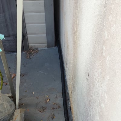 צינור שחור על רצפה ליד קיר חיצוני