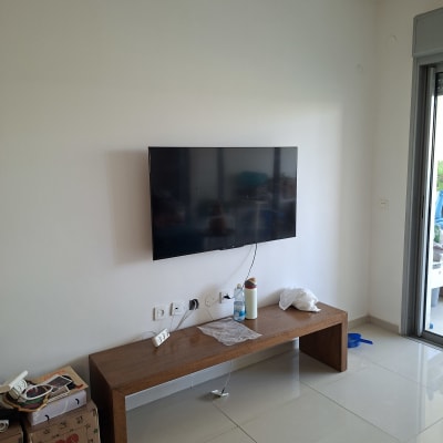 טלוויזיה מותקנת על קיר עם שולחן עץ וכבלים