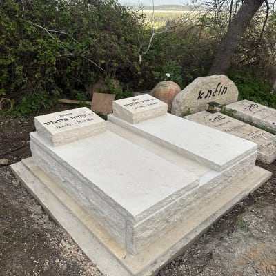 קברים מאבן לבנה עם כיתוב בעברית בבית קברות