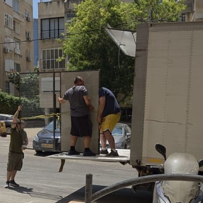 אנשים מעמיסים רהיט למשאית ברחוב עירוני