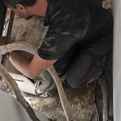 אדם עובד על מערכת מיזוג אוויר עם צינורות וחוטים