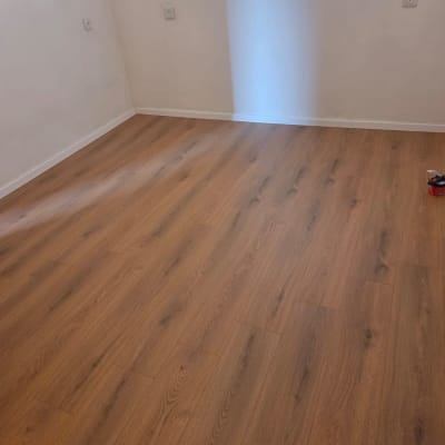 רצפת פרקט בחדר עם חלון ותריסים