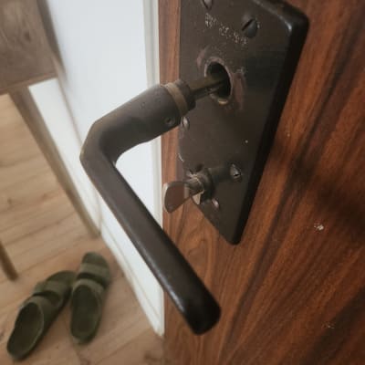 ידית דלת מתכתית על דלת עץ