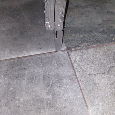 יד מחזיקה כלי רב תכליתי על רצפת אריחים