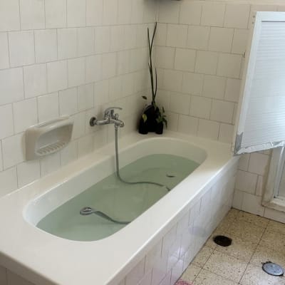 אמבטיה עם חיפוי אריחים לבנים ומדף עם בקבוקים