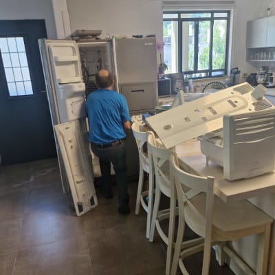 אדם מתקן מקרר במטבח עם חלקים מפורקים