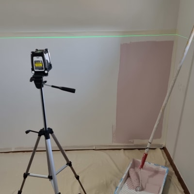 רולר צביעה במגש צבע ורוד על רצפה מכוסה בניילון