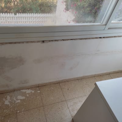 קיר עם תיקוני טיח וכתמי צבע מתקלפים