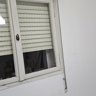 תריסים לבנים סגורים על חלון עם מסגרת לבנה