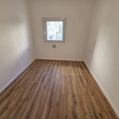 חדר ריק עם רצפת פרקט וחלון קטן
