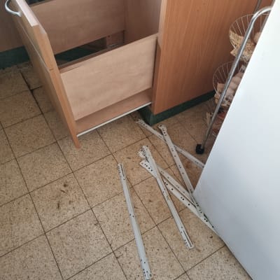 מגירה פתוחה עם מסילות מתכת מפורקות על הרצפה