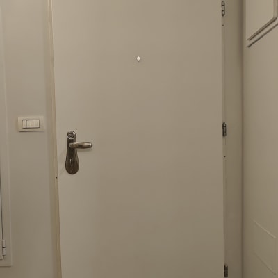 דלת לבנה עם ידית מתכת, רצפה מכוסה בנייר