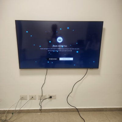 טלוויזיה מותקנת על קיר עם כבלים מחוברים לשקעים