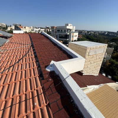 גג רעפים אדומים עם קורות לבנות וצל כבלים