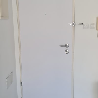 דלת לבנה עם ידית מתכת ובריח עליון