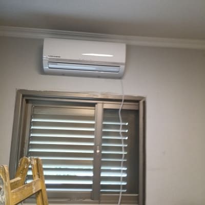 מזגן מותקן מעל חלון עם תריסים